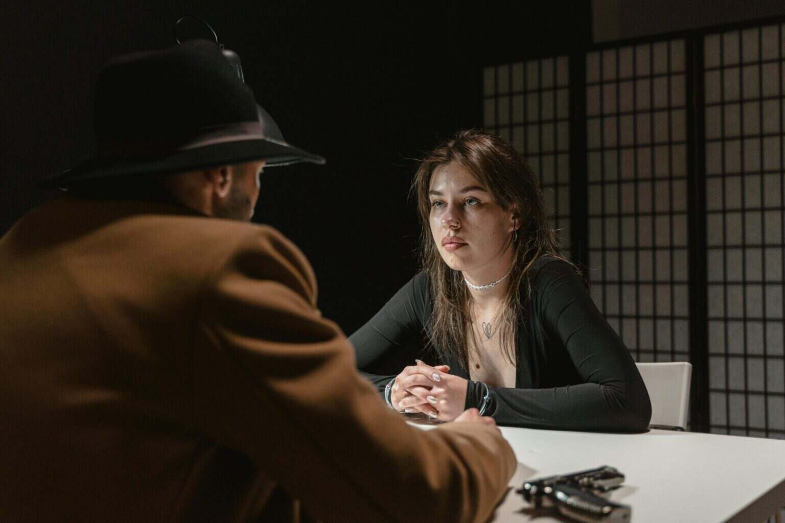 The Pitt Saison 2 : Le Drame Médical Qui Marque Encore par Son Alliance d’Empathie et de Maîtrise A woman faces a man in a hat during a tense interrogation scene at a table.