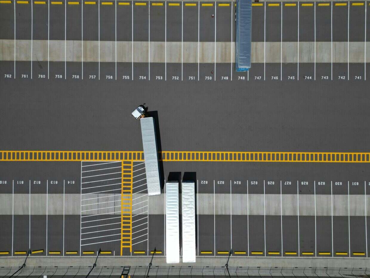 Comprendre l’agrégation WAN : une définition essentielle An aerial view of a large parking lot with lined spaces and semi-trucks.