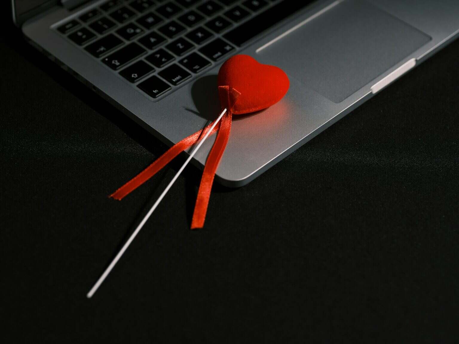 Quel comparateur de site de rencontre choisir pour éviter les pièges ? a heart shaped lollipop sitting on top of a laptop computer