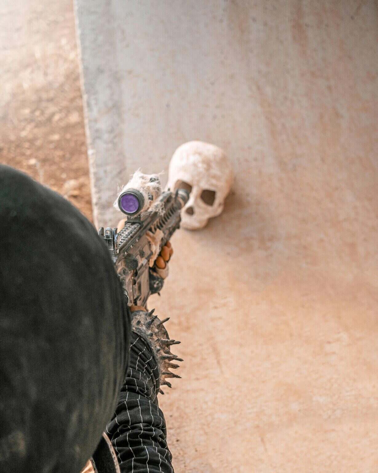 A futuristic soldier in a cyberpunk setting aims at a skull in a desert landscape.