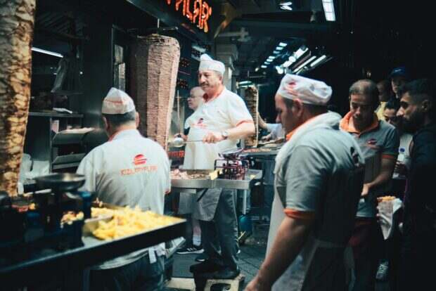 Chefs preparing traditional doner kebab at a busy night street food stall in Istanbul.