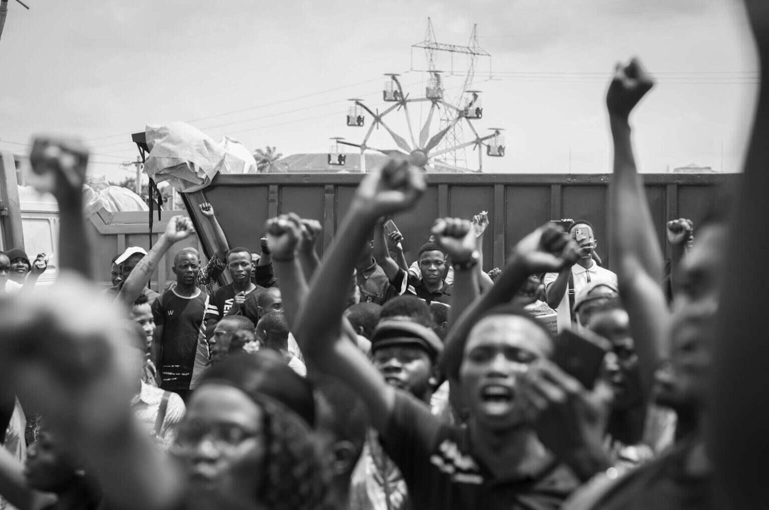 Black and white photo of a large crowd raising fists, showcasing unity in protest.