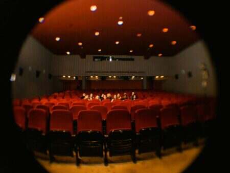 A fisheye lens captures moviegoers in a dimly lit cinema, offering a unique perspective.