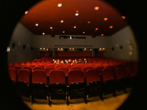 A fisheye lens captures moviegoers in a dimly lit cinema, offering a unique perspective.