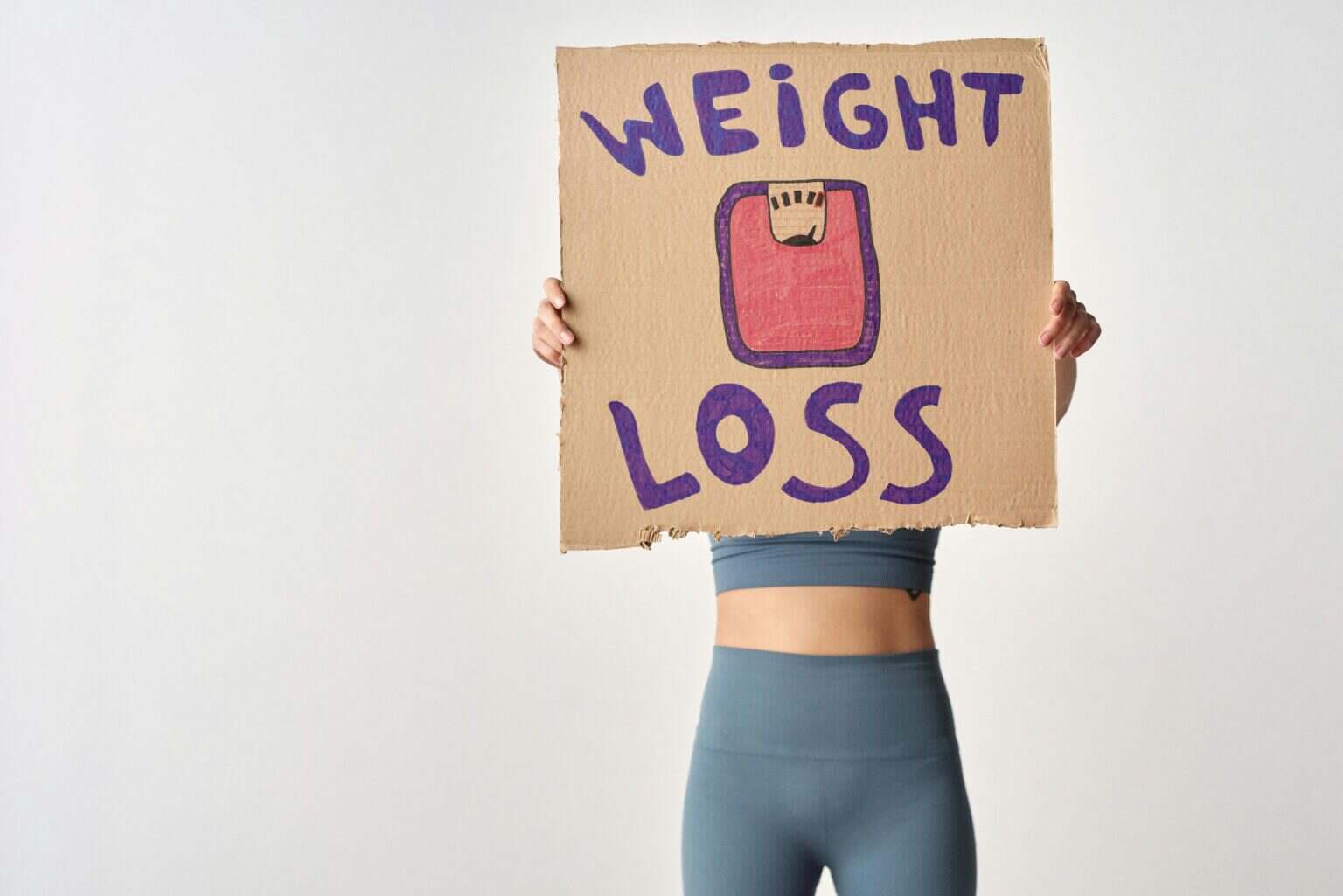 Person holding 'weight loss' sign for fitness motivation and health goals.