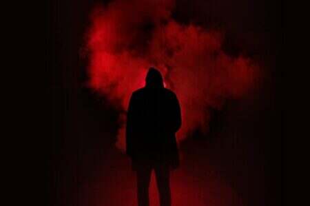 A mysterious silhouette standing against a backdrop of dramatic red smoke.
