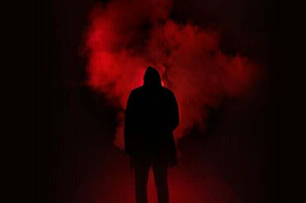 A mysterious silhouette standing against a backdrop of dramatic red smoke.