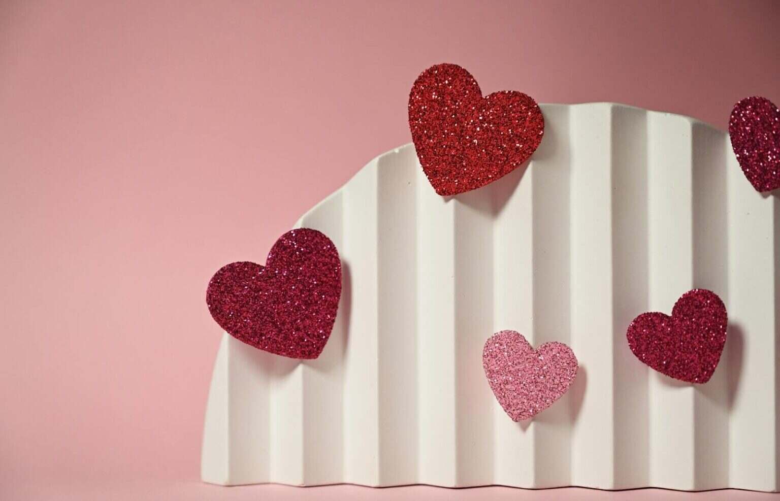 Keanu Reeves et sa femme Alexandra Grant : la love story qu’Hollywood n’avait pas vu venir Glittery heart decorations on a white textured surface with a pink background, perfect for Valentine's themes.