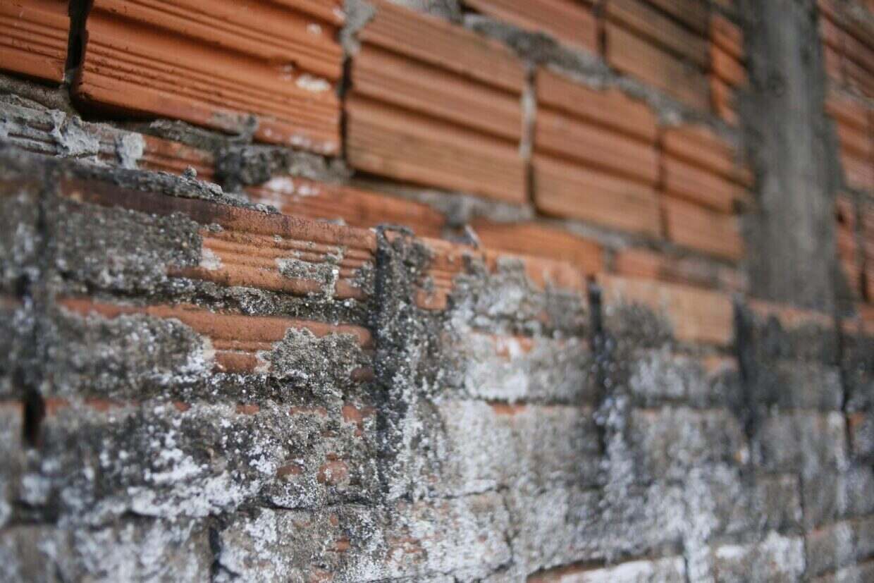 Detailed close-up of a weathered red brick wall with visible decay and texture.