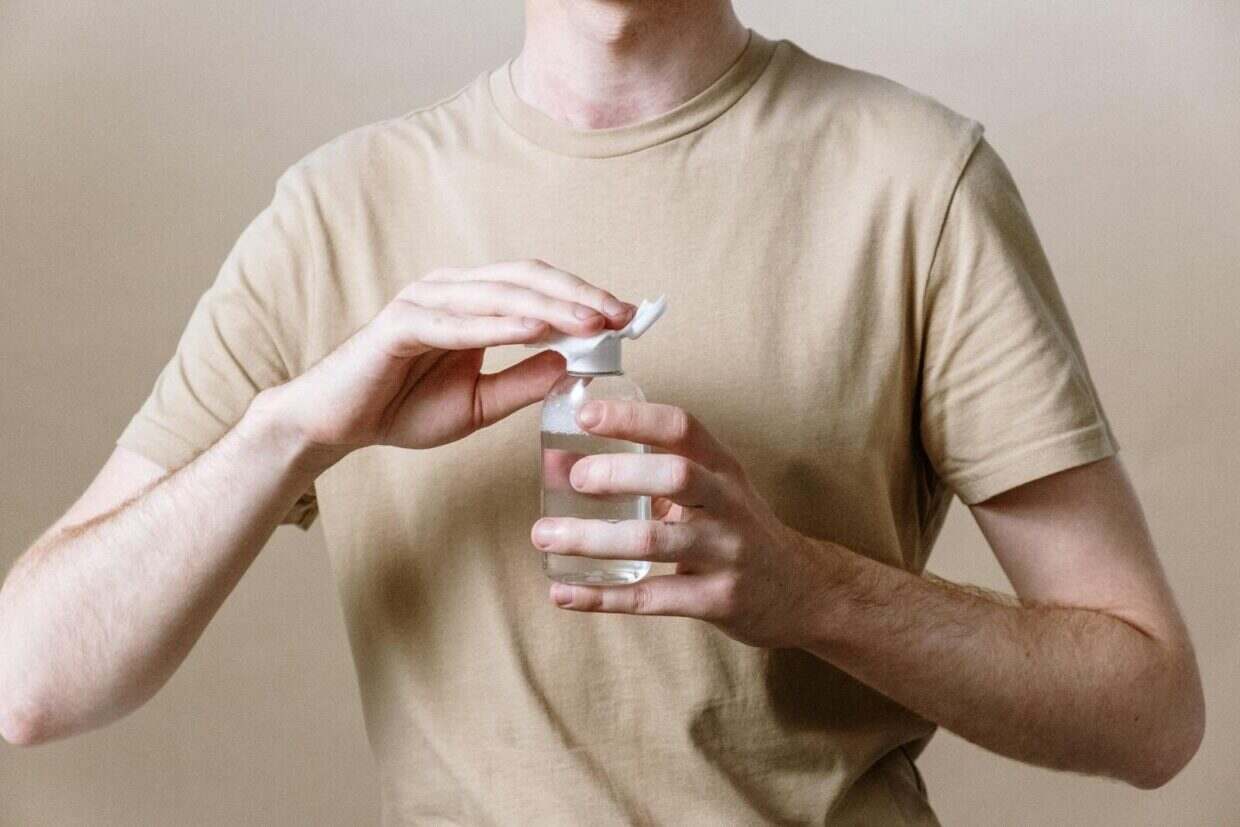 Adult male opening a bottle of micellar water, representing a skincare routine.