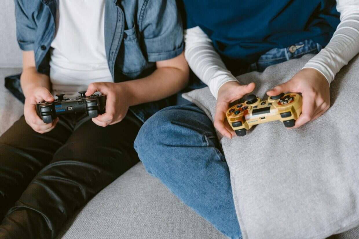 Two teenagers absorbed in console gaming indoors, focused on controllers.