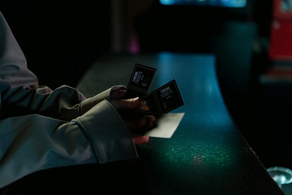 Moody image of a person holding cinema tickets at night, highlighting anticipation of a movie night.