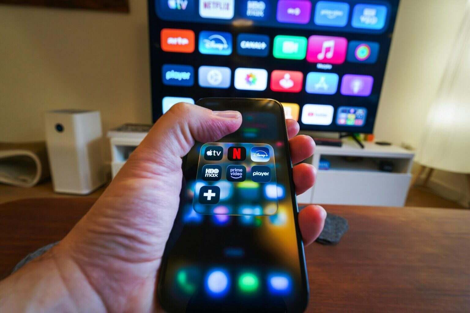 Genius Browse : Apple TV règle enfin le problème que tout le monde a mais que personne ne nomme Hand holding smartphone controlling smart TV apps