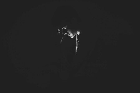 A solitary man is captured in a black and white moody setting, evoking feelings of loneliness and introspection.