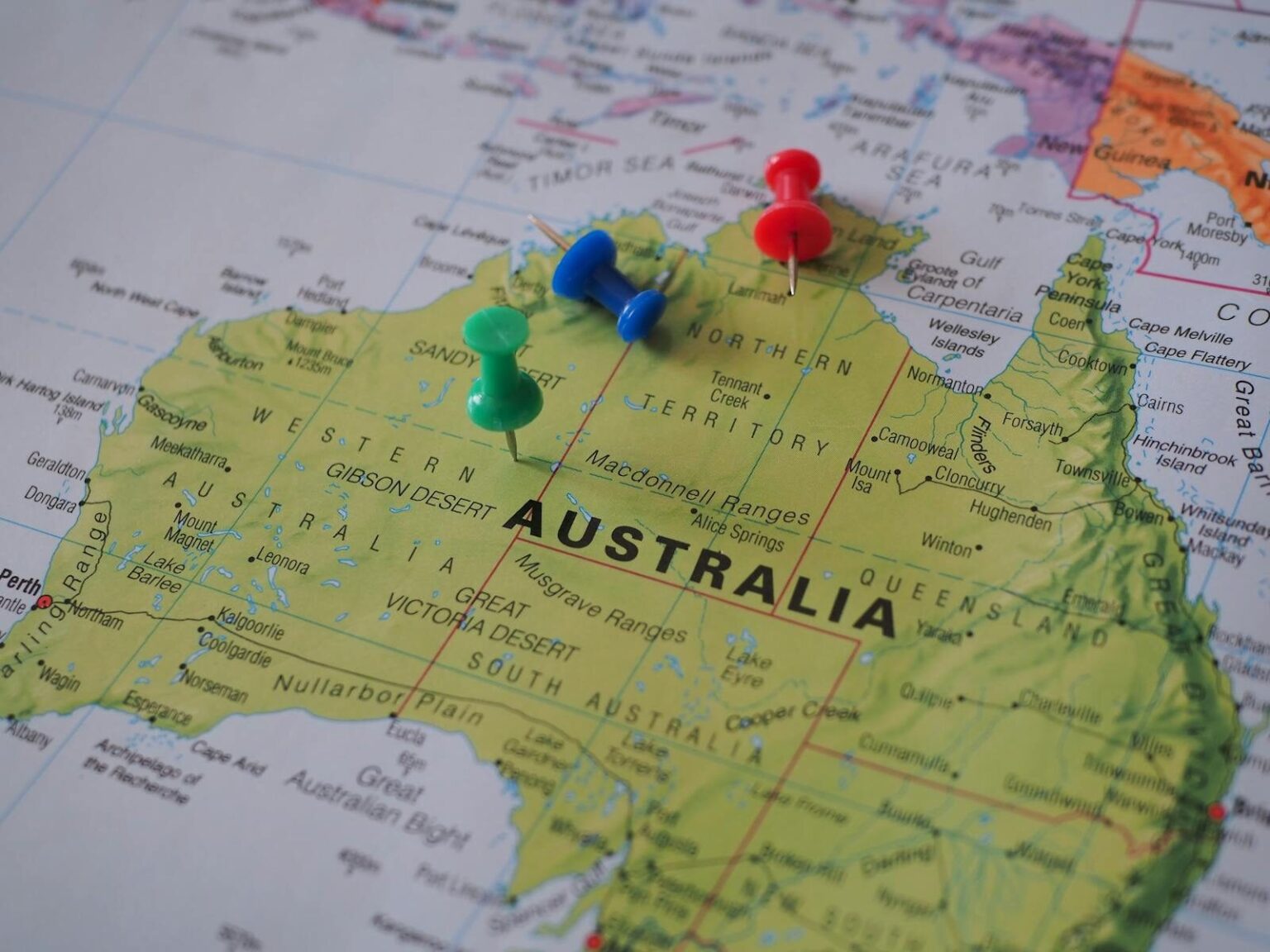 Close-up of a map of Australia featuring colorful pushpins marking locations.
