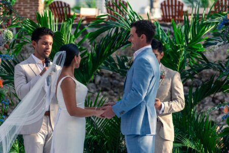 Bride and groom exchanging vows outdoors in a lush, tropical setting.