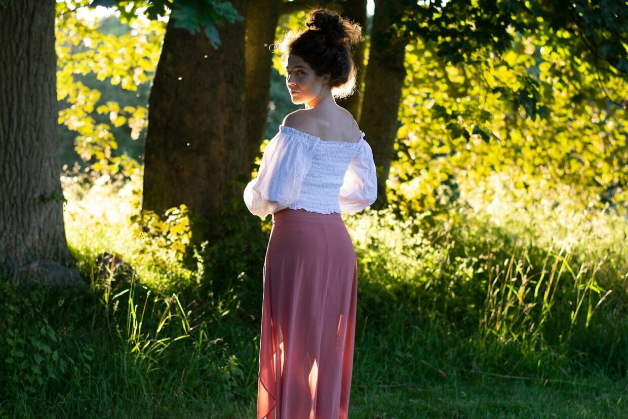 A woman in a long skirt standing in the grass