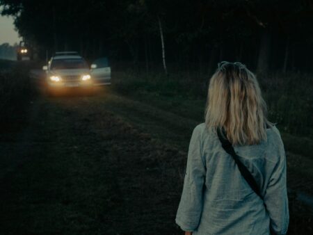 a woman standing in front of a car at night