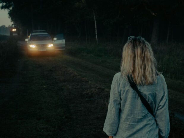 a woman standing in front of a car at night
