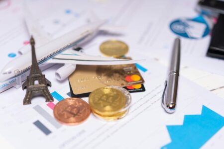 A travel finance concept featuring cryptocurrency, credit card, airplane model, and Eiffel Tower on financial documents.