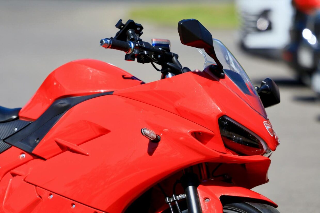 Close-up view of a sleek red sports motorcycle on a sunny day, showcasing its aerodynamic design.