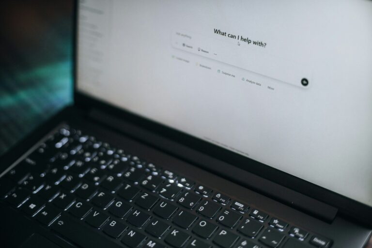 A laptop displays "what can i help with?"