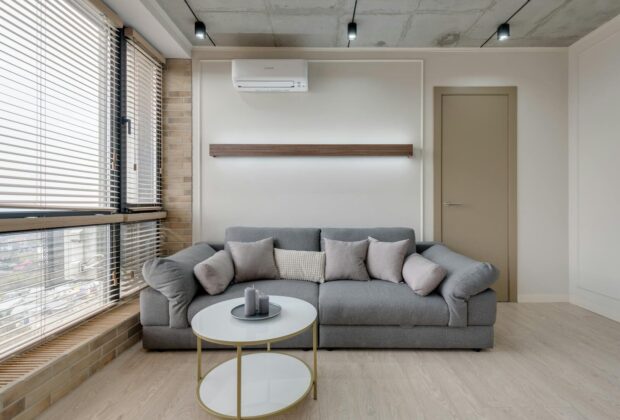 Canapé d’angle ou modulable : le grand duel du salon, et y’a un gagnant Minimalist living room with grey sofa, pillows, and modern decor.