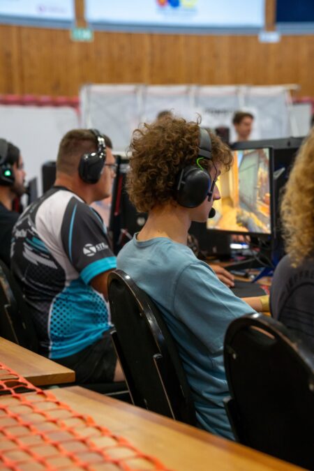 Compétitions esport : business, prize pools, sponsors, droits TV Players wearing headphones focused on video gaming at a competitive esports event indoors.