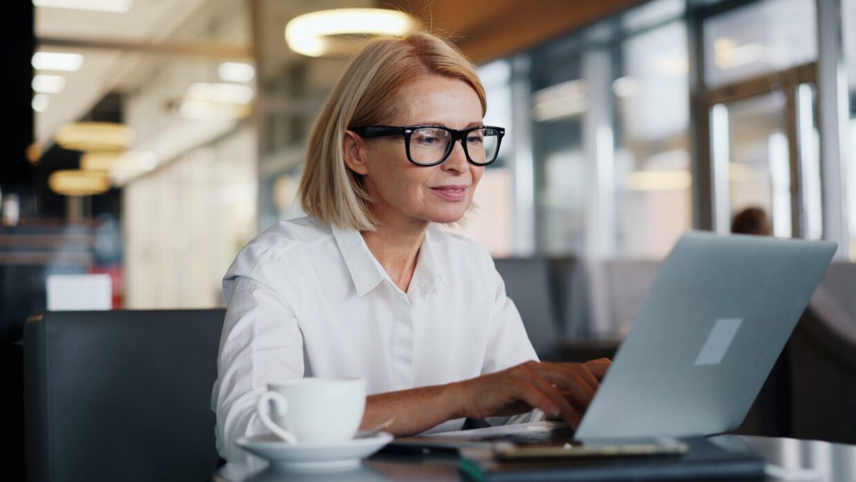 a woman sitting at a table using a laptop computer