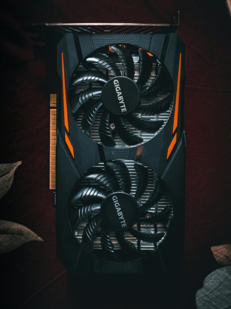 La carte graphique pour l’IA : laquelle choisir selon votre budget et vos besoins Detailed close-up of a black and orange graphic card with cooling fans.