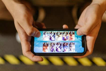 Meilleurs jeux mobile gratuit : Top des jeux incontournables à télécharger sur smartphone Close-up of hands playing a mobile game on a smartphone, showcasing the game's interface.