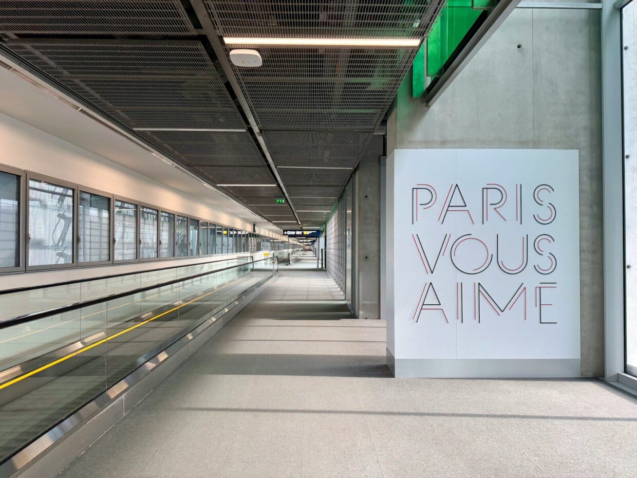 CDG Express : le train Paris-Roissy en 20 minutes, 24 euros le billet et quinze ans de couac Modern airport walkway with "paris vous aime" art