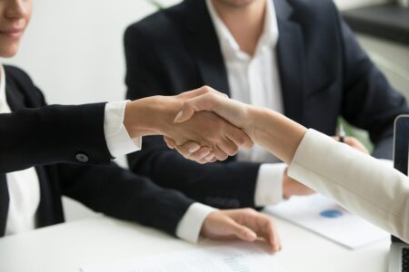 Crédit conso : ce que personne ne vous dit avant de signer two people shaking hands in front of a laptop