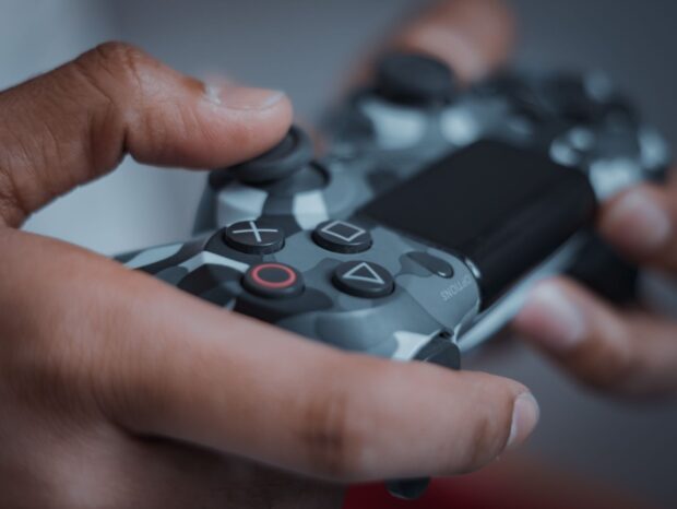 Detailed shot of hands gripping a camouflage game controller, perfect for gaming themes.