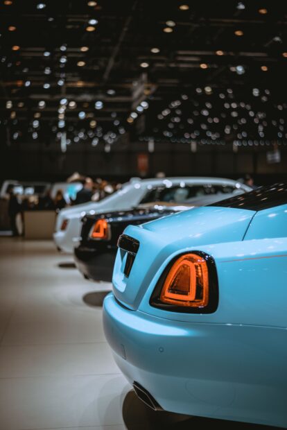 Mondial de l’Auto 2026 à Paris : dates, constructeurs présents et infos pratiques Rear view of luxury cars lined up at an indoor auto show with bright lighting.
