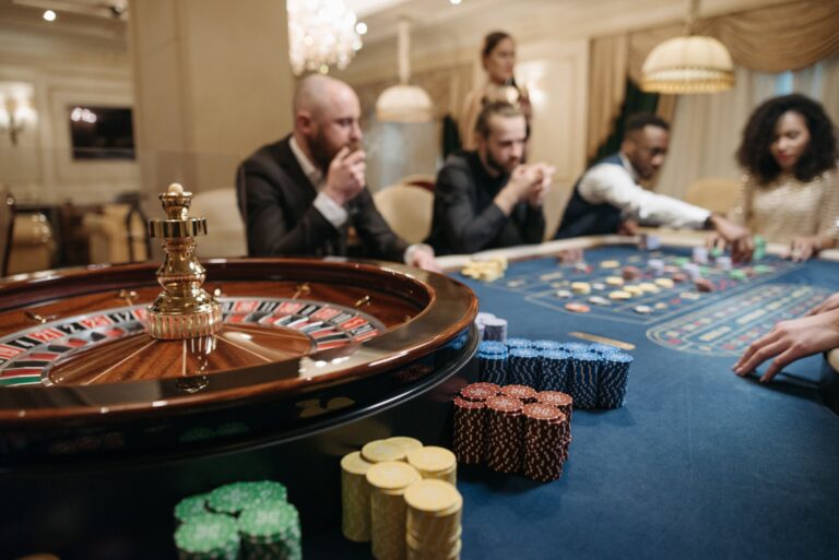 Machines à sous, roulette, blackjack : dans les casinos physiques, qui rafle la mise People enjoying a roulette game in an upscale casino setting with chips and a roulette wheel.
