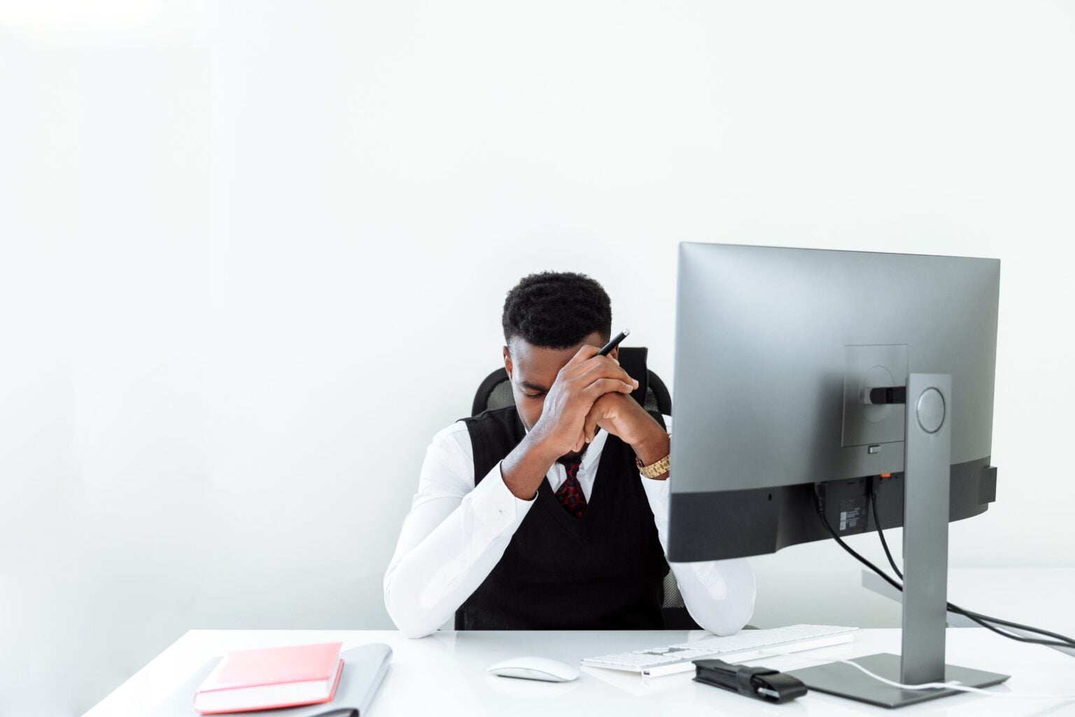 Réduire le stress quotidien : ce qui marche vraiment, ce qui ne sert à rien, et pourquoi 64 % des Français sont encore à bout A businessman sitting at a desk, appearing stressed while working at a computer in a bright office.
