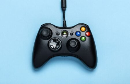 Comment la gamification a conquis Internet (et notre cerveau avec) Black video game controller isolated on a blue background for gaming enthusiasts.