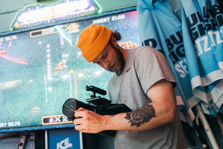 Les meilleurs films français sur le jeu : une sélection pour les passionnés Man with tattoo filming in an arcade, using professional camera equipment.