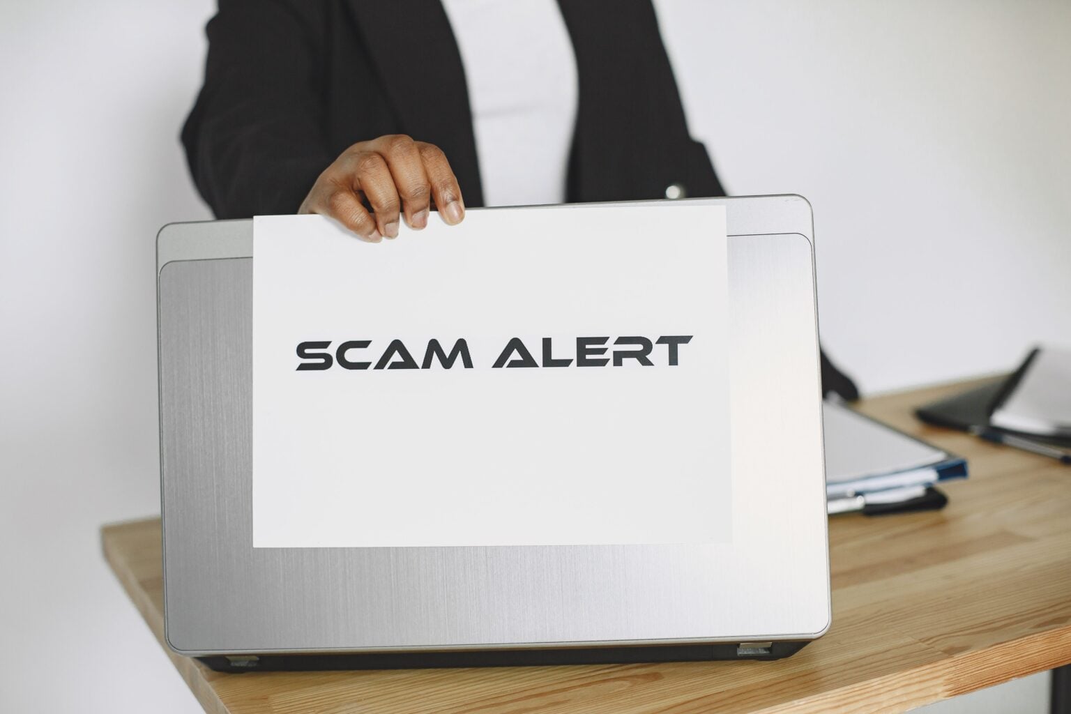 Arnaque au prélèvement de 69 euros : comment cette escroquerie ultra-crédible vide les comptes des Français depuis le 15 juin 2026 Business person holding a scam alert sign over a laptop, warning against online fraud.