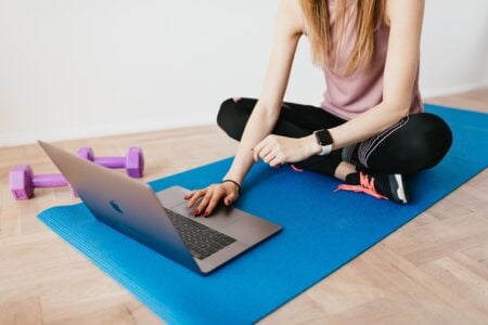 Business de la formation en ligne : CPF, arnaques, infopreneurs et vrais organismes sérieux en France Faceless female in activewear sitting on blue yoga mat on floor and browsing laptop