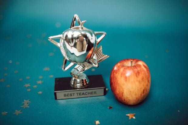Idées cadeaux maîtresse et ATSEM : remerciements de fin d’année scolaire, originaux et pas chers Silver star-shaped trophy with apple on a blue background for teacher appreciation.