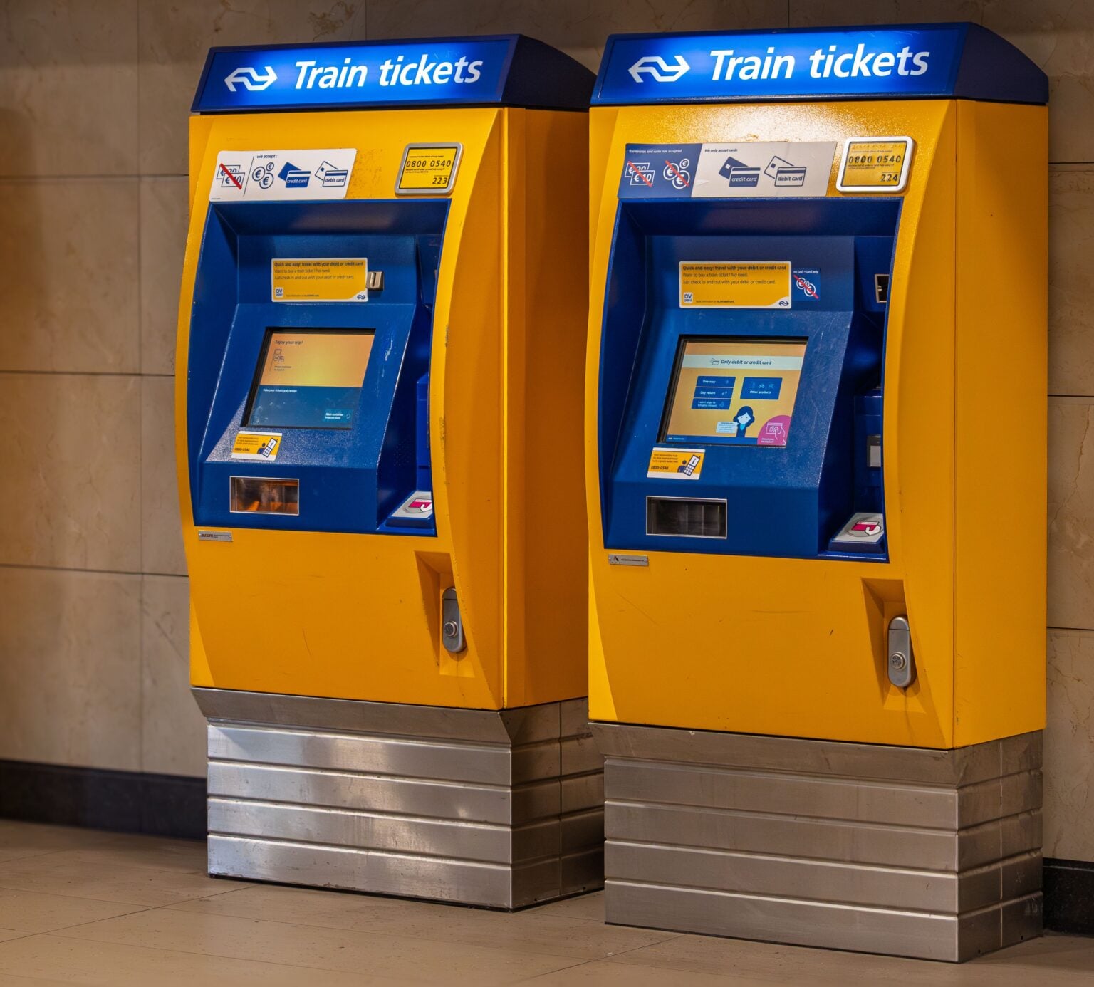 Vente flash SNCF : 100 000 billets TGV Inoui à 19 € pour août 2026 Two vibrant yellow and blue train ticket machines in an indoor station setting.
