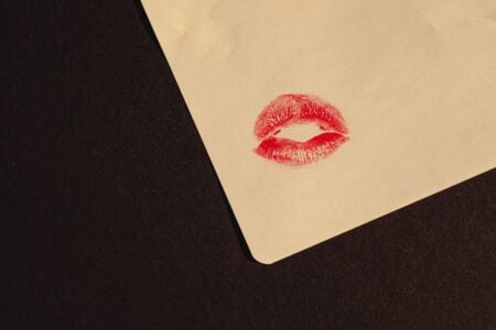 Comment draguer une fille par SMS ? Close-up of a red lipstick kiss imprint on paper with copy space, symbolizing romance and affection.