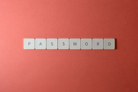 Gestionnaire de mot de passe : pourquoi 94% se font piéger et comment y échapper Focus on password security with white keyboard tiles spelling 'PASSWORD' on a coral background.