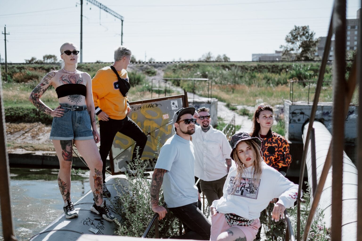 Fashionable group posing in streetwear by an industrial outdoor area.