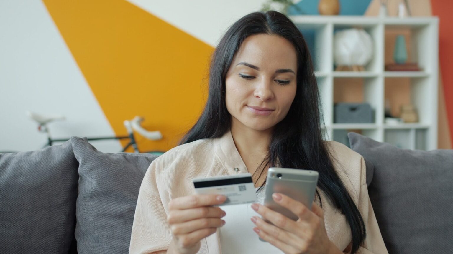 Pourquoi le prix affiché change selon l’endroit d’où vous le regardez Woman holding credit card and phone for online shopping