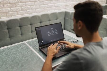 Faut-il intégrer l’IA à tout prix dans son business ? A man working on a laptop in a cozy, modern office space with a focus on technology.