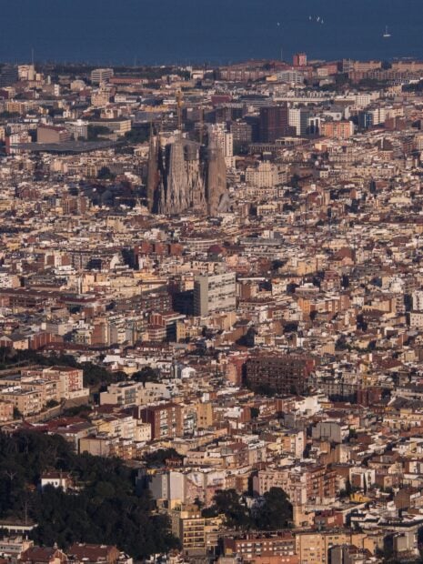 Aerial view of the iconic Sagrada Familia amidst Barcelona's dense cityscape.