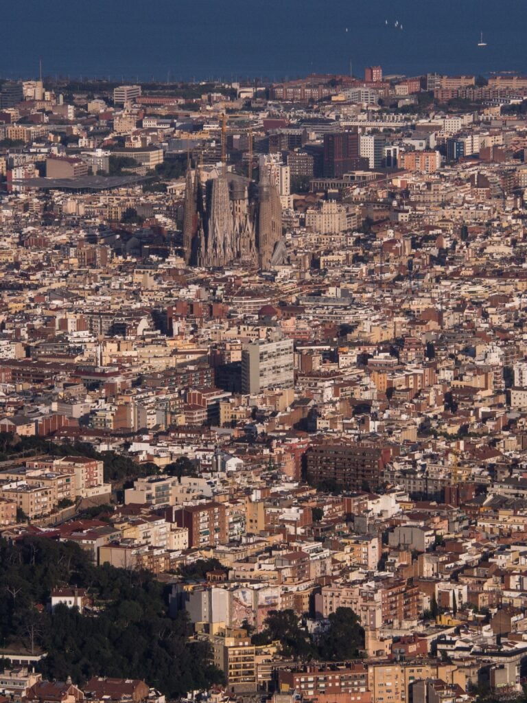 Aerial view of the iconic Sagrada Familia amidst Barcelona's dense cityscape.